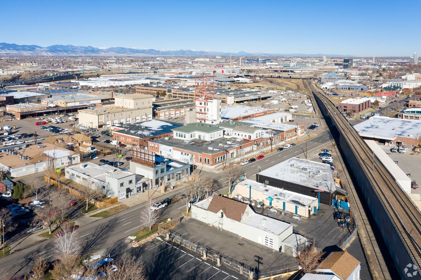 Aerial view of photospace in Denver's Sun Valley — the studio building, the railroad, and the Rocky Mountains on the horizon